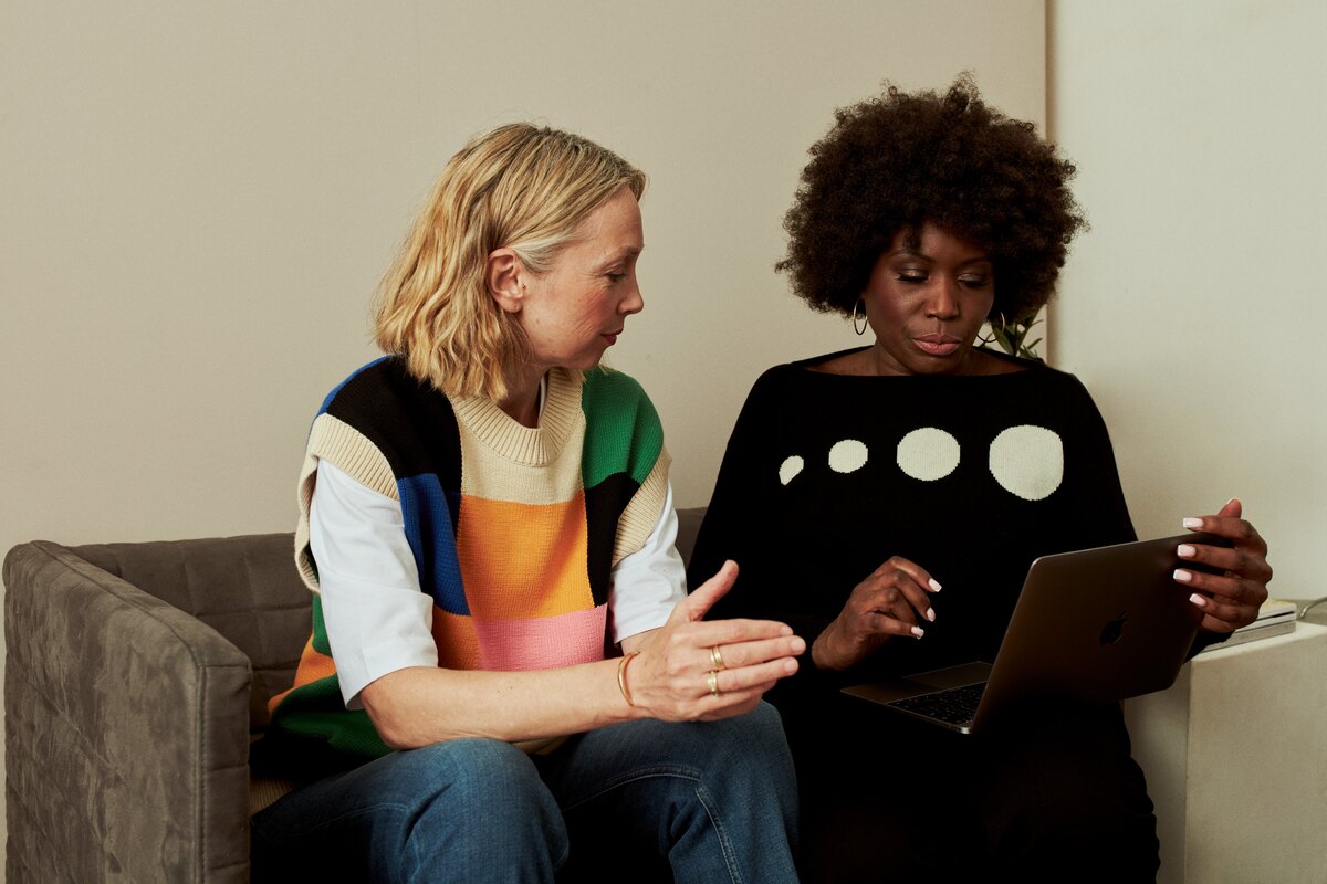Diverse adults, including an African American woman, enjoying warm conversation and companionship together on a living room sofa